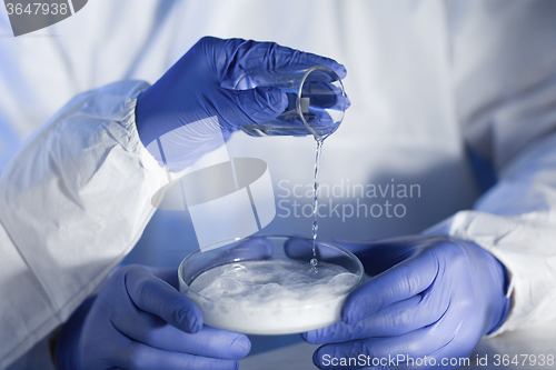 Image of close up of scientists hands with chemicals in lab