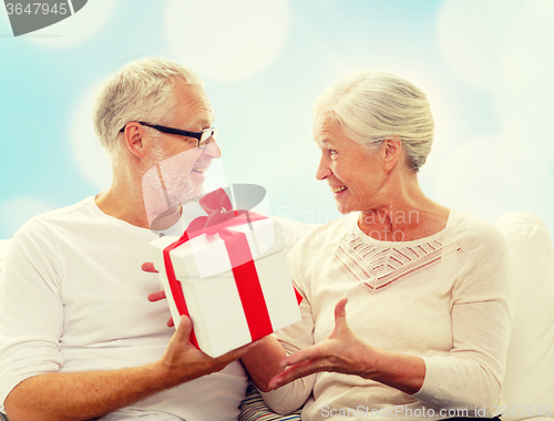 Image of happy senior couple with gift box at home