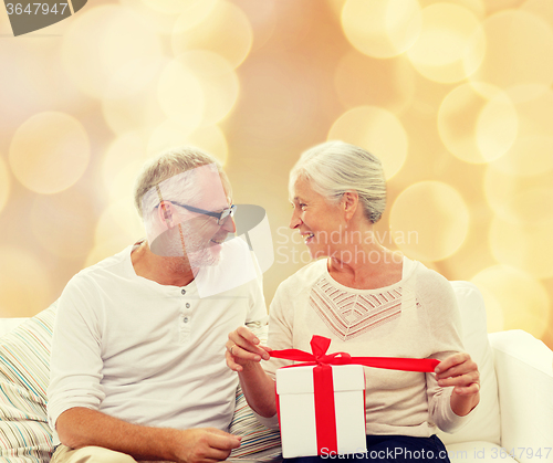 Image of happy senior couple with gift box at home