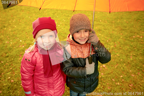 Image of happy boy and girl with umbrella in autumn park