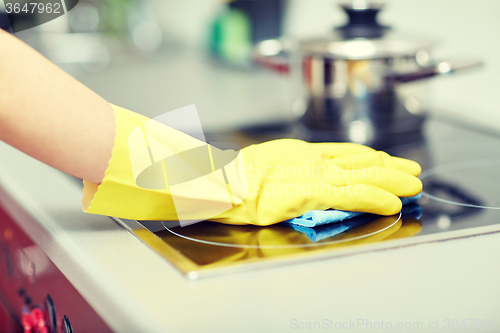Image of close up of woman cleaning cooker at home kitchen
