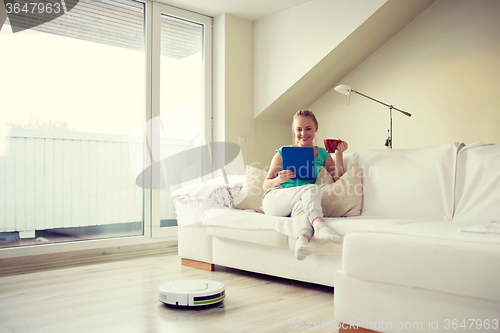 Image of happy woman with tablet pc drinking tea at home