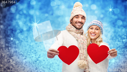 Image of smiling couple in winter clothes with red hearts