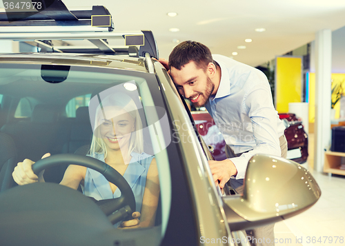 Image of happy couple buying car in auto show or salon