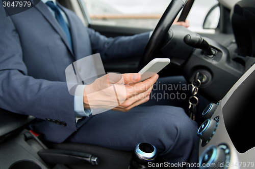 Image of close up of man with smartphone driving car