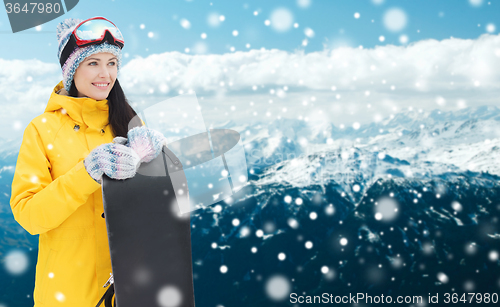 Image of happy young woman with snowboard over mountains