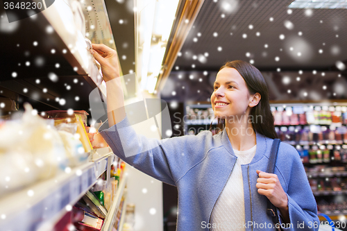 Image of happy woman choosing and buying food in market