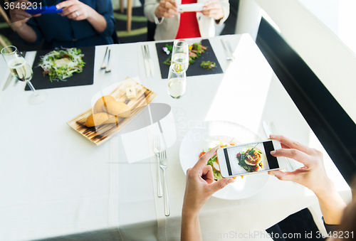 Image of close up of women picturing food by smartphones