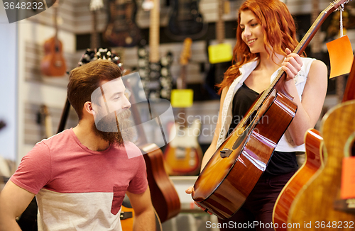 Image of couple of musicians with guitar at music store