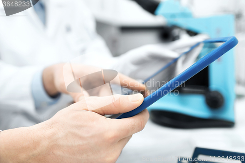 Image of close up of scientists hands with tablet pc in lab