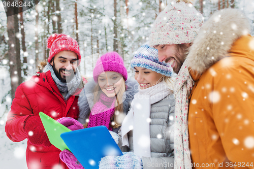 Image of smiling friends with tablet pc in winter forest
