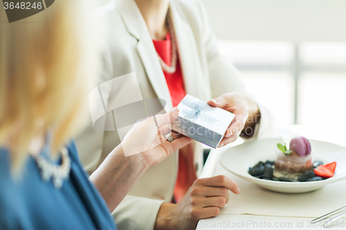 Image of close up of women giving present at restaurant