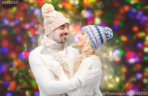 Image of happy couple in winter clothes hugging over lights