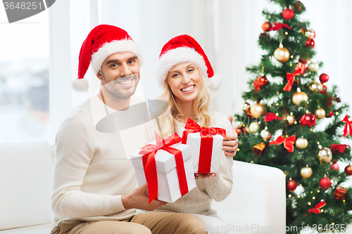 Image of happy couple at home with christmas gift boxes