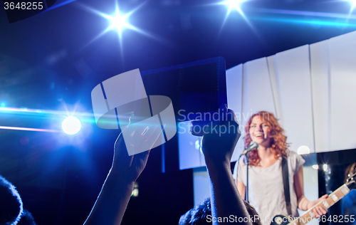 Image of hands with tablet pc taking video of music concert