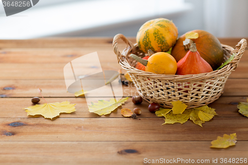 Image of close up of pumpkins in basket on wooden table