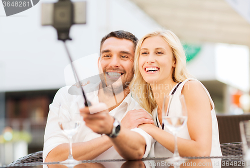 Image of happy couple taking selfie with smartphone at cafe