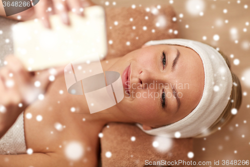 Image of close up of smiling woman with smartphone in spa