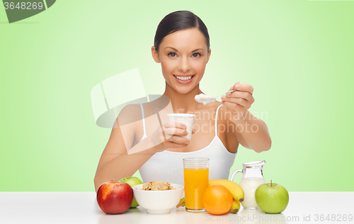 Image of happy woman eating yogurt for breakfast