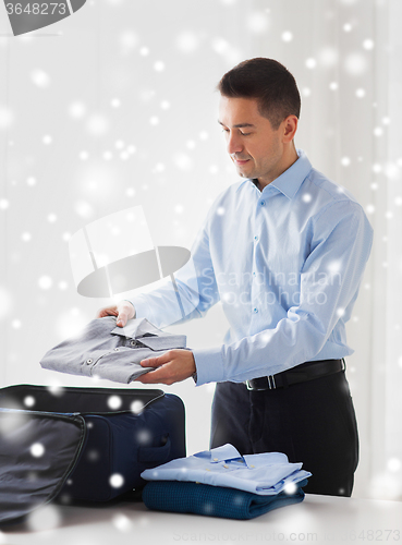 Image of businessman packing clothes into travel bag