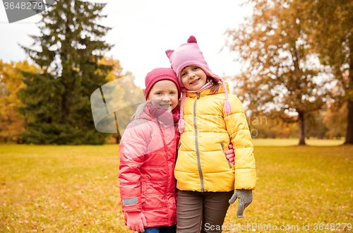 Image of two happy little girls hugging in autumn park