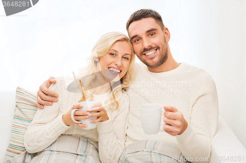 Image of happy couple with cups drinking tea at home