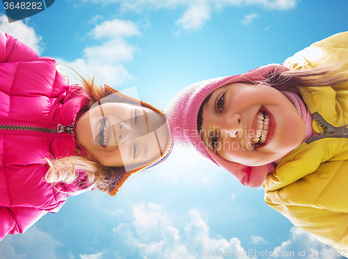 Image of happy little girls faces over blue sky