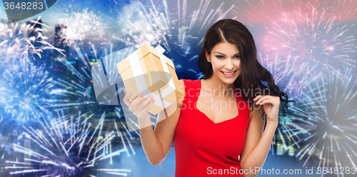 Image of happy woman in red dress with gift over firework