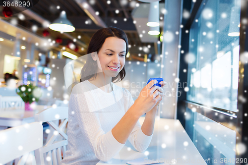 Image of smiling woman with smartphone at cafe