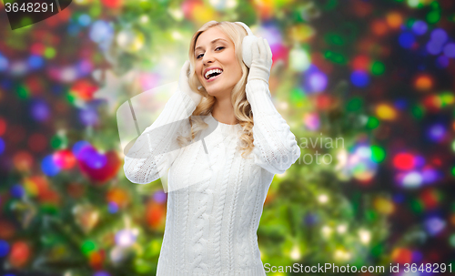 Image of smiling young woman in winter earmuffs and sweater