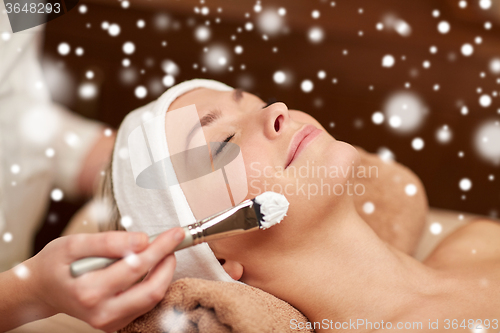Image of woman face and beautician applying mask in spa