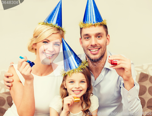 Image of smiling family in blue hats blowing favor horns