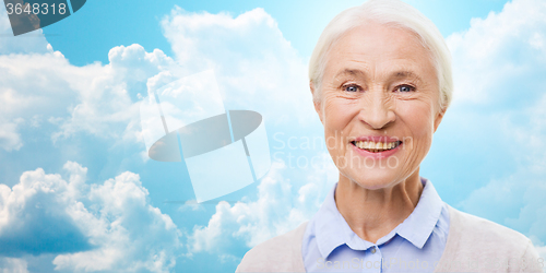 Image of happy senior woman face over blue sky and clouds