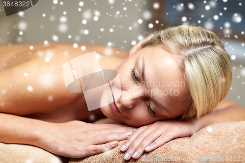Image of young woman lying on massage table in spa salon
