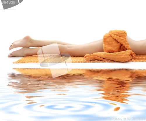 Image of long legs of relaxed lady with orange towel on white sand #3