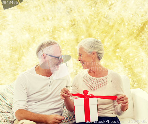 Image of happy senior couple with gift box at home