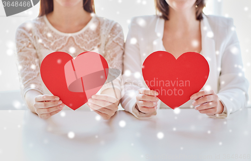 Image of close up of happy lesbian couple with red hearts