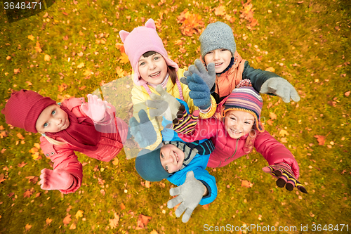 Image of happy children waving hands in autumn park