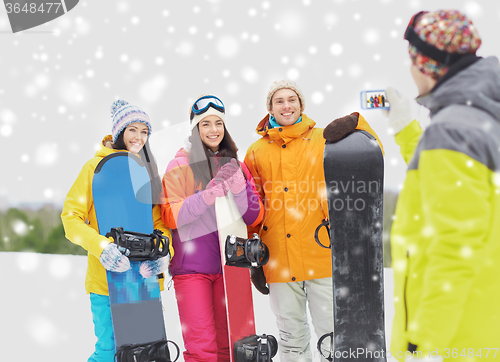 Image of happy friends with snowboards and smartphone