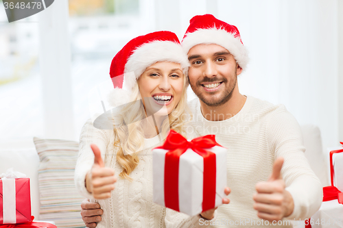 Image of happy couple with christmas gifts and thumbs up