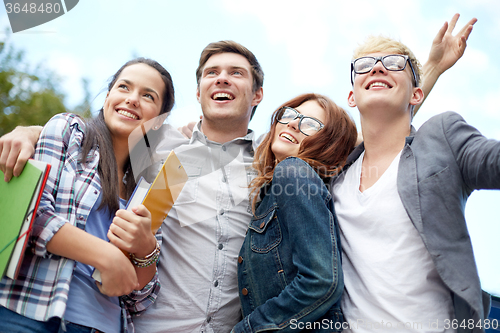 Image of group of happy students with folders outdoors