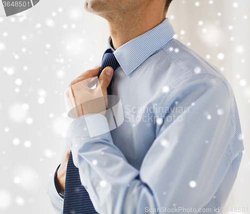 Image of close up of man in shirt adjusting tie on neck