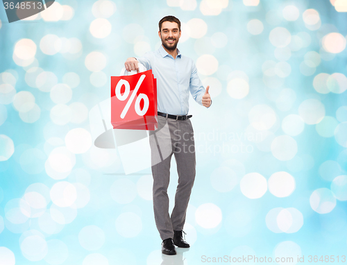 Image of smiling man with red shopping bag over blue lights