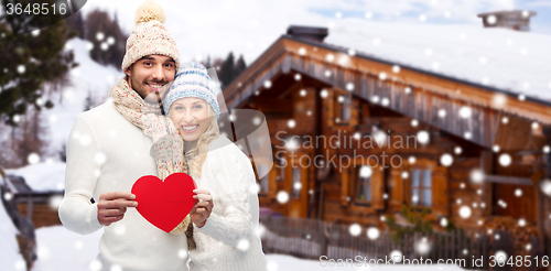 Image of happy couple in winter clothes with heart outdoors