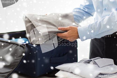 Image of businessman packing clothes into travel bag