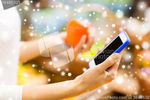 Image of woman with smartphone and persimmon in market