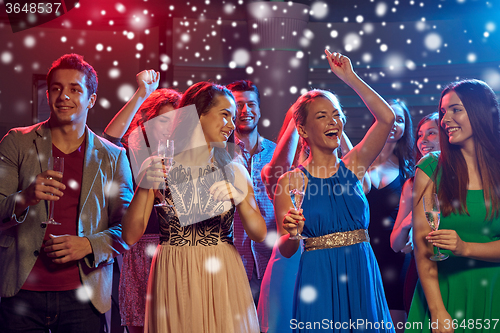 Image of smiling friends with wine glasses and beer in club