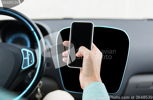 Image of close up of male hand with smartphone driving car