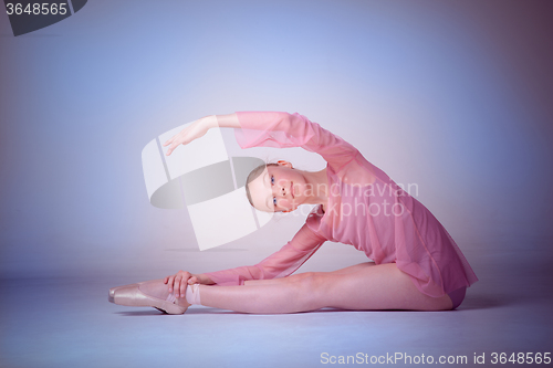 Image of The young ballerina posing on the floor 