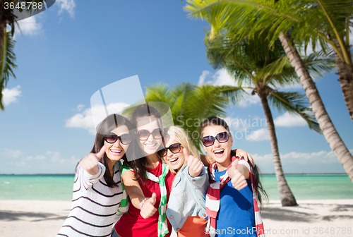 Image of happy teenage girls showing thumbs up on beach